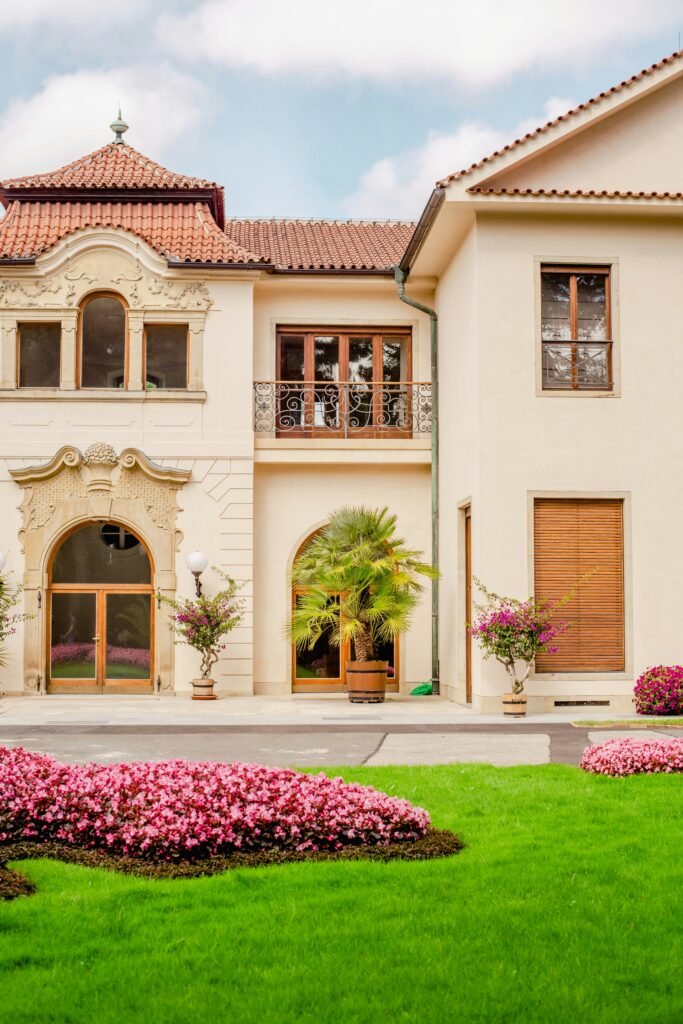 a large white house with pink flowers in front of it 